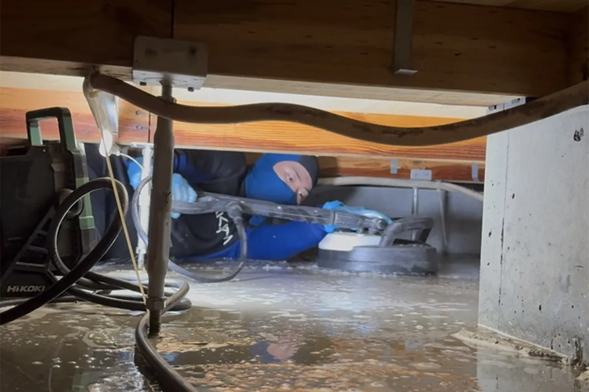 アクサムのスタッフが床を壊さずに専用機材で床下の排水・乾燥・消毒を行っている施工写真