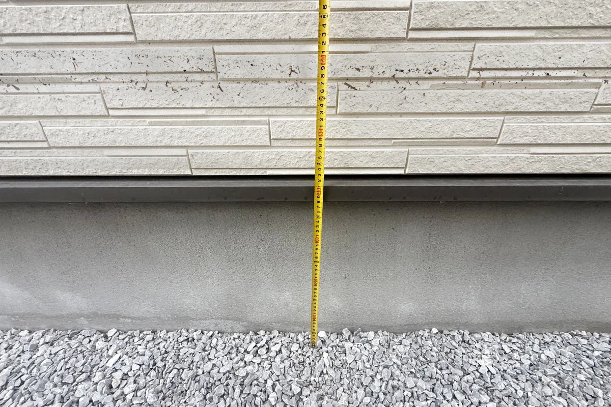 床下浸水の現場でメジャーを当てて地盤面からの浸水高さを計測している写真