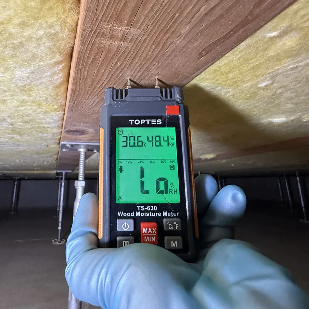 床下で含水率計を使って木材の乾燥状態を測定する作業員